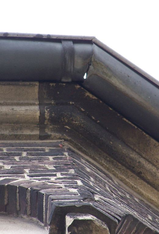 Defekte Dachrinne, sanierungsbedürftiger Naturstein